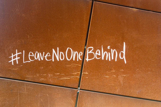 Photo of tiles with writing on it that reads #LeaveNoOneBehind.