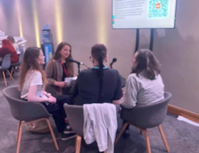 Carolina, Emma, Chloe and Lynne seated around a table with microphones recording the Jisc Community podcast - thanks Jo Fletcher-Saxon for the photo!