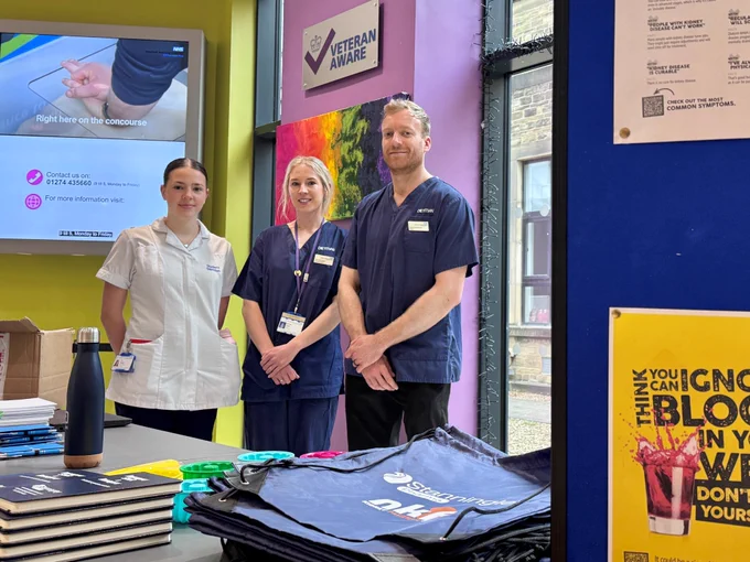 Three members of the team stand behind a table with information on it.