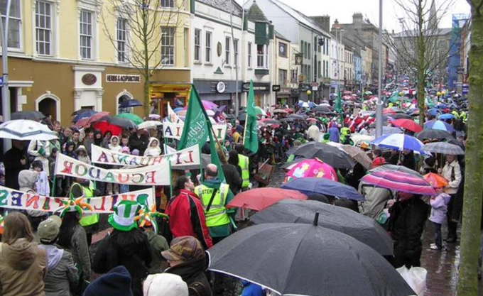 Street with Patrick's Day marchers and observers with umbrellas