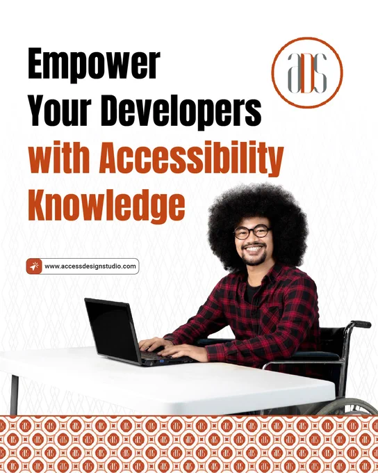 A man is sitting in a wheelchair with his laptop on a table and is smiling.
