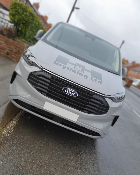 Front of a grey Ford Transit, featuring 'H&H Drylining Ltd' dark grey graphics on the bonnet.