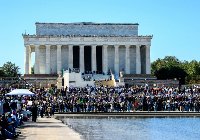 An image of the Lincoln Memorial in Washington, D.C. on a sunny day with blue sky and thousands of people in the surrounding area.