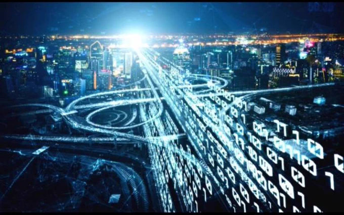 Futuristic city skyline at night with glowing orange and yellow light trails weaving through streets, suggesting digital connectivity and high tech environment.