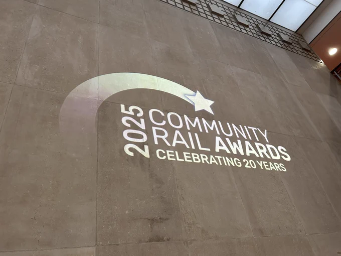Photo showing the Community Rail Awards logo projected on a big wall.