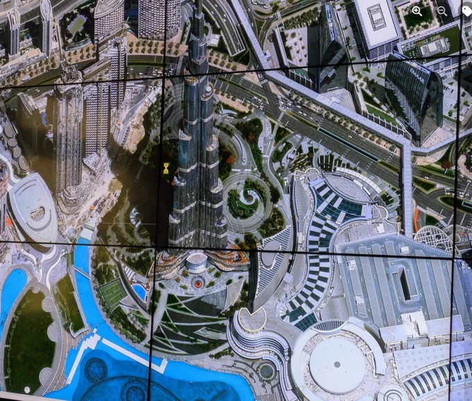 Close up satellite view of central Dubai showing buildings, the road system and a lake at the foot of the image.