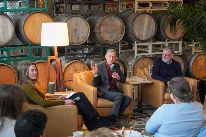 Mayor Wilson holding a microphone, while sitting next to City Administrator Michael Jordan and discussion moderator Sarah Schiffman at the Central Eastside Industrial Council quarterly event 