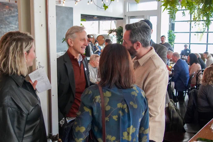 Mayor Wilson standing in a small group, chatting with attendees of the Central Eastside Industrial Council quarterly event