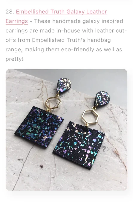 Leather drop earring laying on a slab of marble. The leather has an abstract metallic foil print.