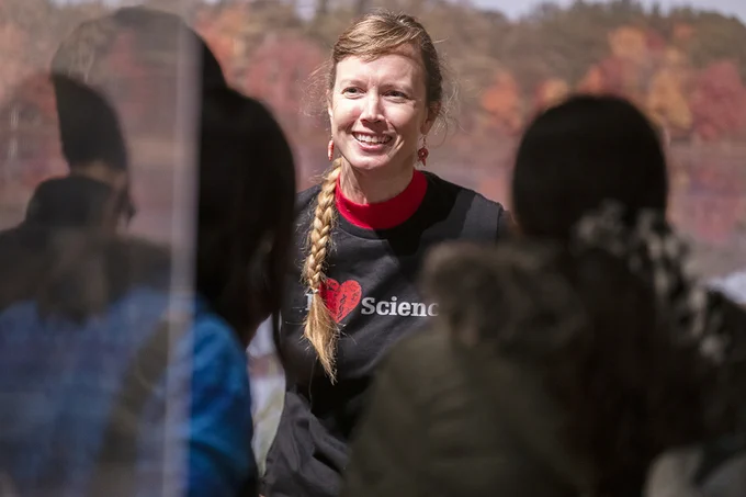 Photograph of a woman with a long braid smiling and speaking to museum visitors
