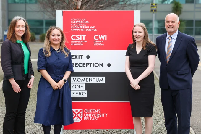 Image shows pictured left to right: Judith Millar, Business Development Manager CSIT; UK Government Minister for AI and Digital Government Feryal Clark; Professor Máire O'Neill, Director CSIT, Professor Paul Millar, Deputy Director CSIT. They are standing beside the CSIT signage.