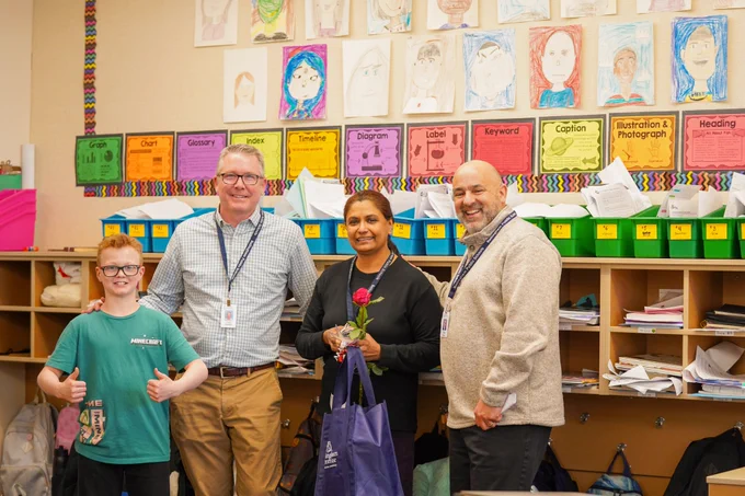 A teacher honored alongside superintendent, principal and a student in a classroom