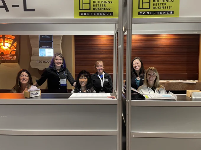 Registration desk at the Buildings: Better Business Conference with staff members smiling behind the counter.