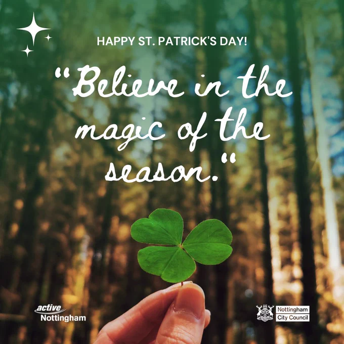 A hand holding a three-leaf clover in front of a blurred forest background. The text at the top reads 'HAPPY ST. PATRICK'S DAY!' Below it, in larger cursive font, is the quote 'Believe in the magic of the season.' At the bottom left corner, there is an Active Nottingham logo. In the bottom right corner, there is a Nottingham City Council logos.