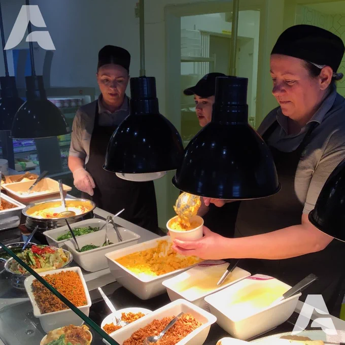 Three members of the catering serving food.