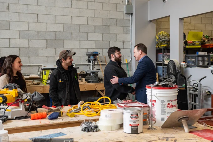 The Honorable Steven MacKinnon, Minister of Employment, Workforce Development and Labour shaking hands with a student of the Construct program.