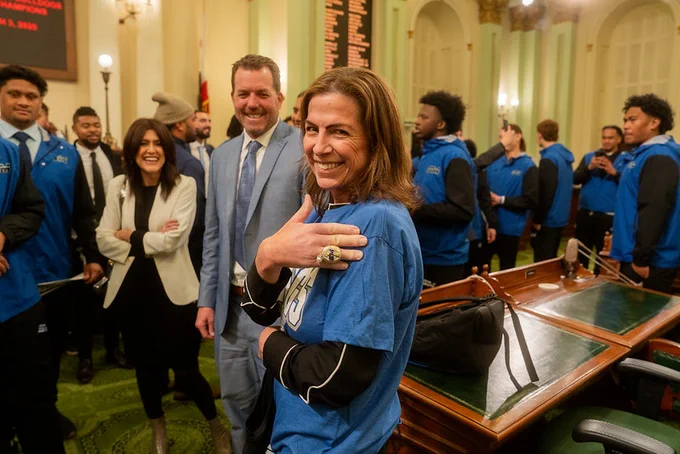 Assemblymember Papan pictured trying on the 2024 championship ring of the College of San Mateo Bulldogs football team next to team head coach Tim Tulloch and San Mateo County Community College District Chancellor Melissa Moreno.