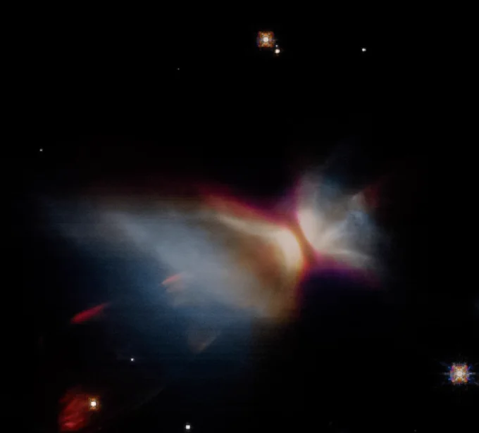 This infrared image shows a faint, hazy nebula surrounding the protostar CB-26. The nebula has wispy clouds of red, orange, and white, set against a dark background sprinkled with stars. Two brighter stars shine near the top, and a smaller, redder nebula can be seen at the bottom left.