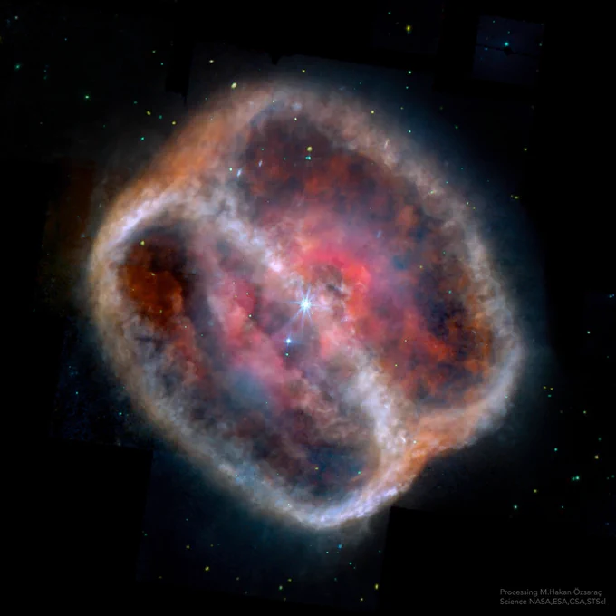This mid-infrared image from MIRI showcases the planetary nebula NGC 1514, often called Crystal Ball Nebula. It appears as a roughly spherical, glowing cloud with a complex structure. The nebula exhibits a range of colors, from a bright white outer shell to a mottled interior of red, pink, and blue hues, suggesting varying temperatures and compositions of the ejected stellar material. A bright central star is visible at the nebula's core, surrounded by a faint, star-like halo. The dark background is sprinkled with a few distant stars, while the bottom right corner of the image includes text stating "Processing M. Hakan Özsaraç Science NASA, ESA, CSA, STScI".