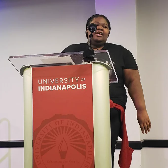 student Lizzie introducing April Gibson  wearing a uindy shirt 