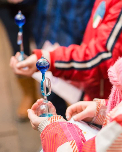 A close up image of children's hands holding a hand boiler with blue liquid bubbling into the top chamber.