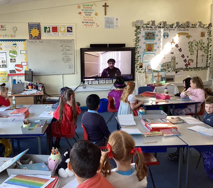 Class of school children watching the quiz on an interactive white board. 
