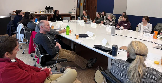 teachers around a rectangular long table listen to speaker
