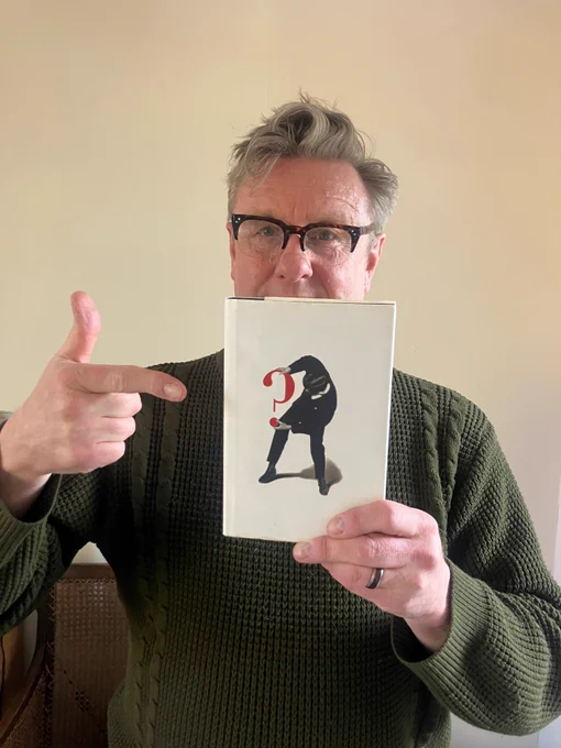 a man holding up a book and pointing to it