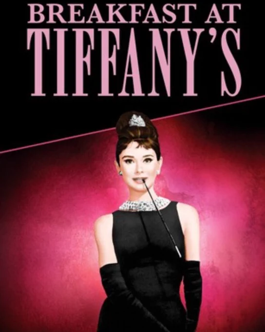 Audrey Hepburn, a young woman with dark hair is shown from the thighs up. She is wearing a sparkly tiara, a pearl choker, black dress, long black gloves, and held in her mouth is a cigarette in a long black holder.