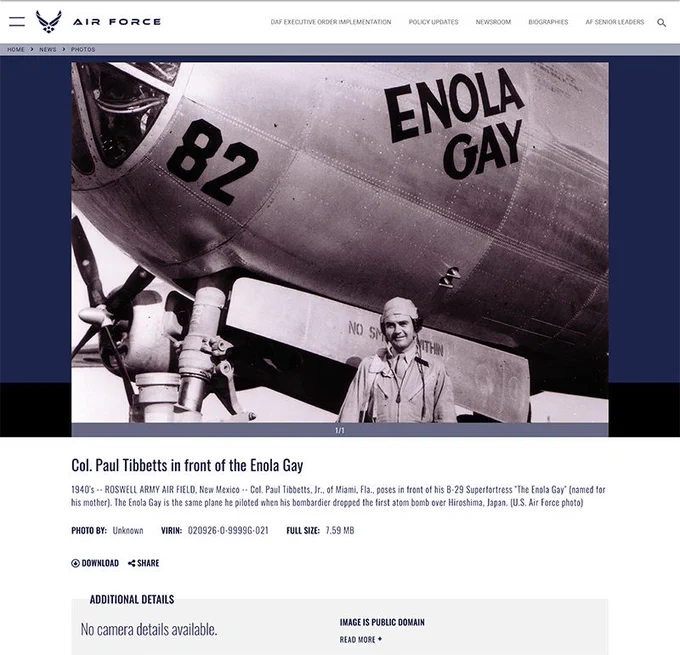 “Black and white photograph of Col. Paul Tibbets standing in front of the nose of the B-29 Superfortress bomber Enola Gay. The aircraft’s name is painted in bold letters on the fuselage, along with the number 82. Tibbets, wearing a military uniform and cap, is smiling. The Enola Gay was the plane he piloted when it dropped the first atomic bomb on Hiroshima, Japan, in 1945. The image is a historical U.S. Air Force photo.”