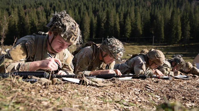 A photograph of four Soldiers lying on the ground and plotting coordinates on a map. (Photo Credit: Pfc. Daely Goodwin, U.S. Army Southern European Task Force, Africa) 