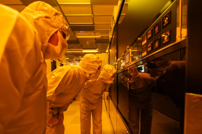 Secretary of State Peter Kyle and technicians in PPE suits inspecting equipment in a semiconductor fabrication facility.