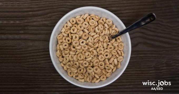 Image: bowl of toasted oat cereal Os with milk and a spoon; Wisc.Jobs AA/EEO