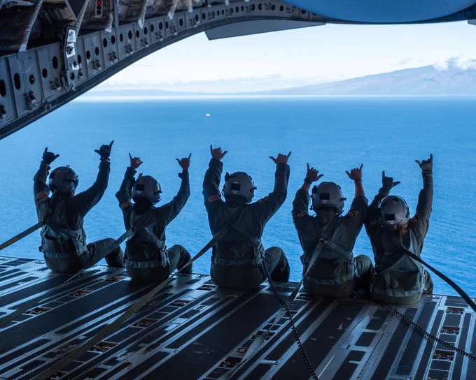 Hawaii Air National Guard Airmen from the 204th Airlift Squadron gather aboard a C-17 Globemaster III as they fly around the Hawaiian Islands. The Airmen throw the “shaka,” a gesture of aloha, to a boat spotted below. 