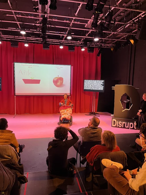 Young lady on stage presenting with disrupt logo to the right
