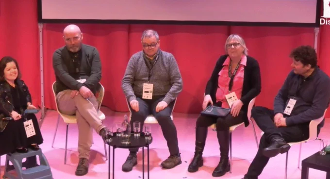 A panel of five people on a stage in a semi-circle