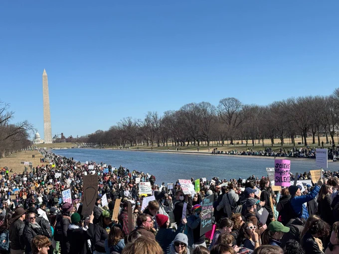 View of gathering crowd for science across reflecting pool  