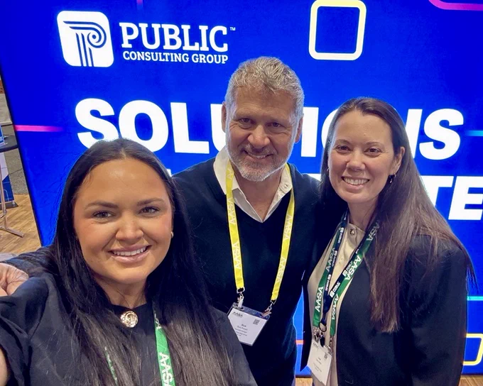 3 people taking a selfie in front of conference booth