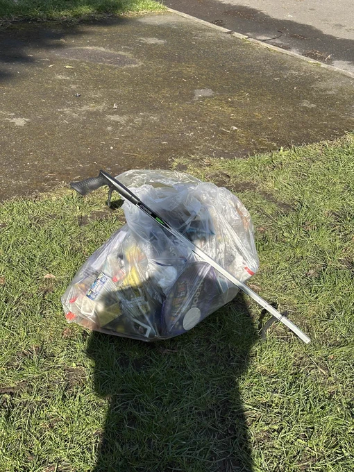 My shadow on a bag of litter, with the litter picker laid across the top