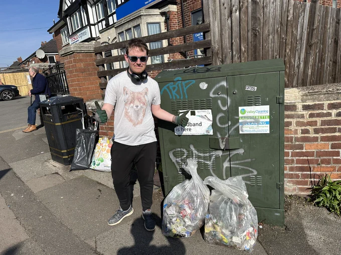 Me posing thumbs up looking cringe next to some bags of litter