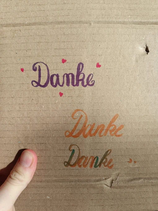 Auf einem Pappkarton wurde 3x "Danke" geschrieben, jeweils mit Brushpens - das heißt, es gibt dickere und dünnere Stellen.
Alles in Schreibschrift.
Das erste Danke ist lila, da herum sind 4 kleine rote Herzchen.
Die nächsten beiden Danke sind kursiv, das erste nur orange das zweite mit Farbverlauf orange/grün.
Links in der Ecke des Bildes ist mein Daumen zu sehen, der den Karton festhält.

Hier schon Teil 1 der Bildbeschreibung des nächsten Bildes:

Collage aus vier Bildern.
Alle zeigen je eine Karte, in der das Wort "Danke" verschiedenartig gestaltet wurde.

Links oben:
In der Mitte "Danke" in pink-grünem Farbverlauf. Am Rand der Karte eine blumenranke in hellbraun mit kleinen hellgrünen Blättern & unterbrochen durch insgesamt 8 großen Blüten, die an Stiefmütterchen/Hornveilchen erinnern, in hellblau mit gelbem Zentrum.