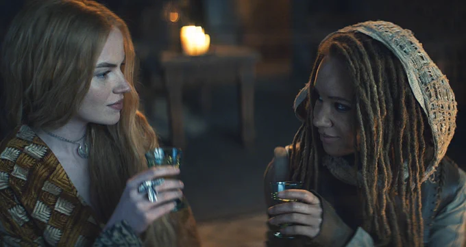 Elayne and Aviendha looking at one another as they raise glasses to toast