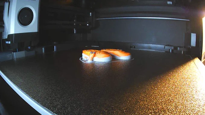 image d'un modèle dans une imprimante 3d, en l'occurrence une paire de chaussure de sport en plusieurs couleurs.
