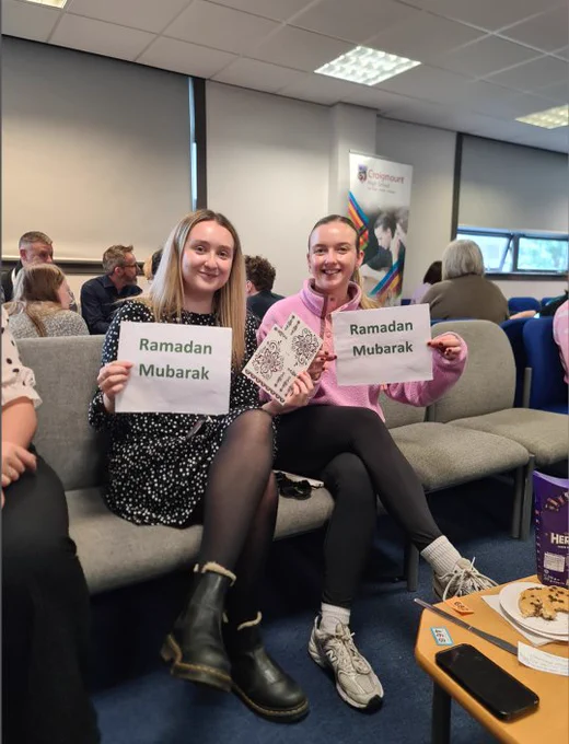 Two teachers pose with Ramadan Mubarak signs
