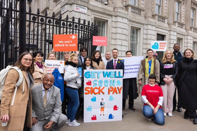 Campaigners stand outside gates to Number 10 Downing Street with the Giant get well soon card, and signs from MS Society, Leukeamia Care and Organise. Credit: Sylvie Pope Photography, Safe Sick Pay campaign