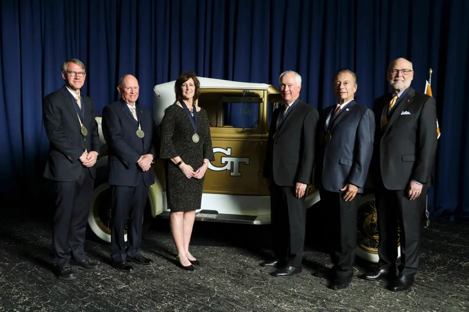 The six Hall of Fame inductees stand with the Ramblin' Wreck against a blue backdrop at the College of Engineering Alumni Awards and Induction Ceremony.