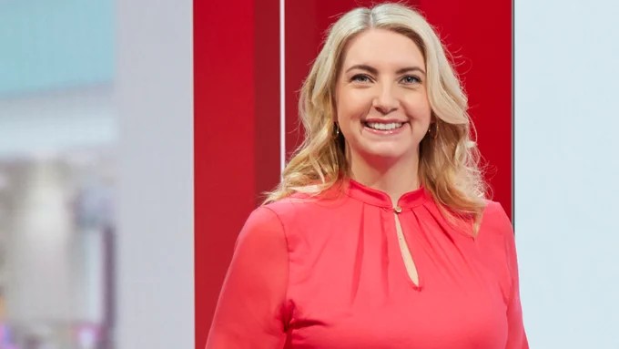 Anna Foster in the studio with a red block and white background behind her. Photo credit: Neil Sherwood