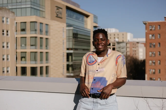 Bongani Ndebele posing for a photo on a rooftop in DC. A building with the George Washington University logo is visible behind him.