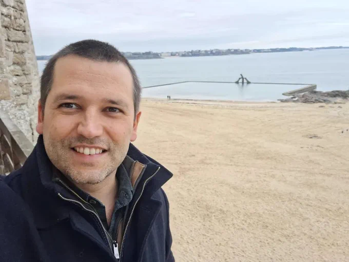 João with a cpat with a pool and the sea in the back, with the weather looking gray and cold.