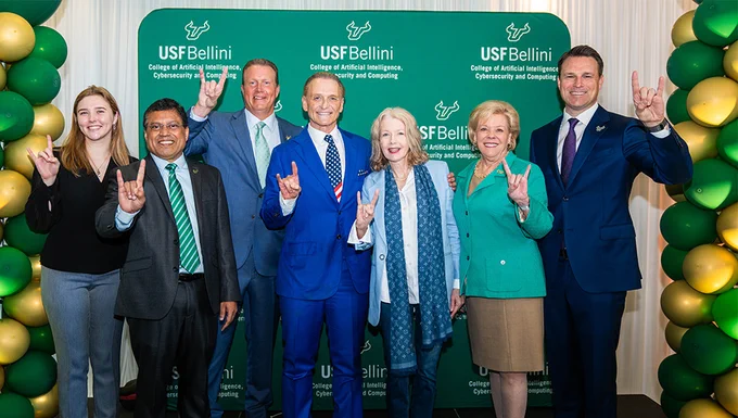 A group poses in front of new USF Bellini College backdrop